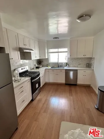 a kitchen with stainless steel appliances granite countertop wooden cabinets stove top oven and sink