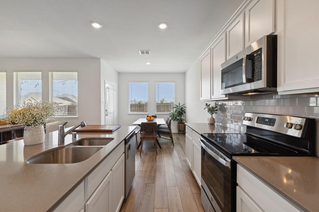705 Alden Drive Princeton, TX 75407 - Photo 10 of 26 a kitchen with stainless steel appliances a sink a stove top oven a sink a dining table and chairs