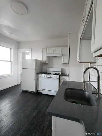 a kitchen with kitchen island a sink white cabinets and stainless steel appliances