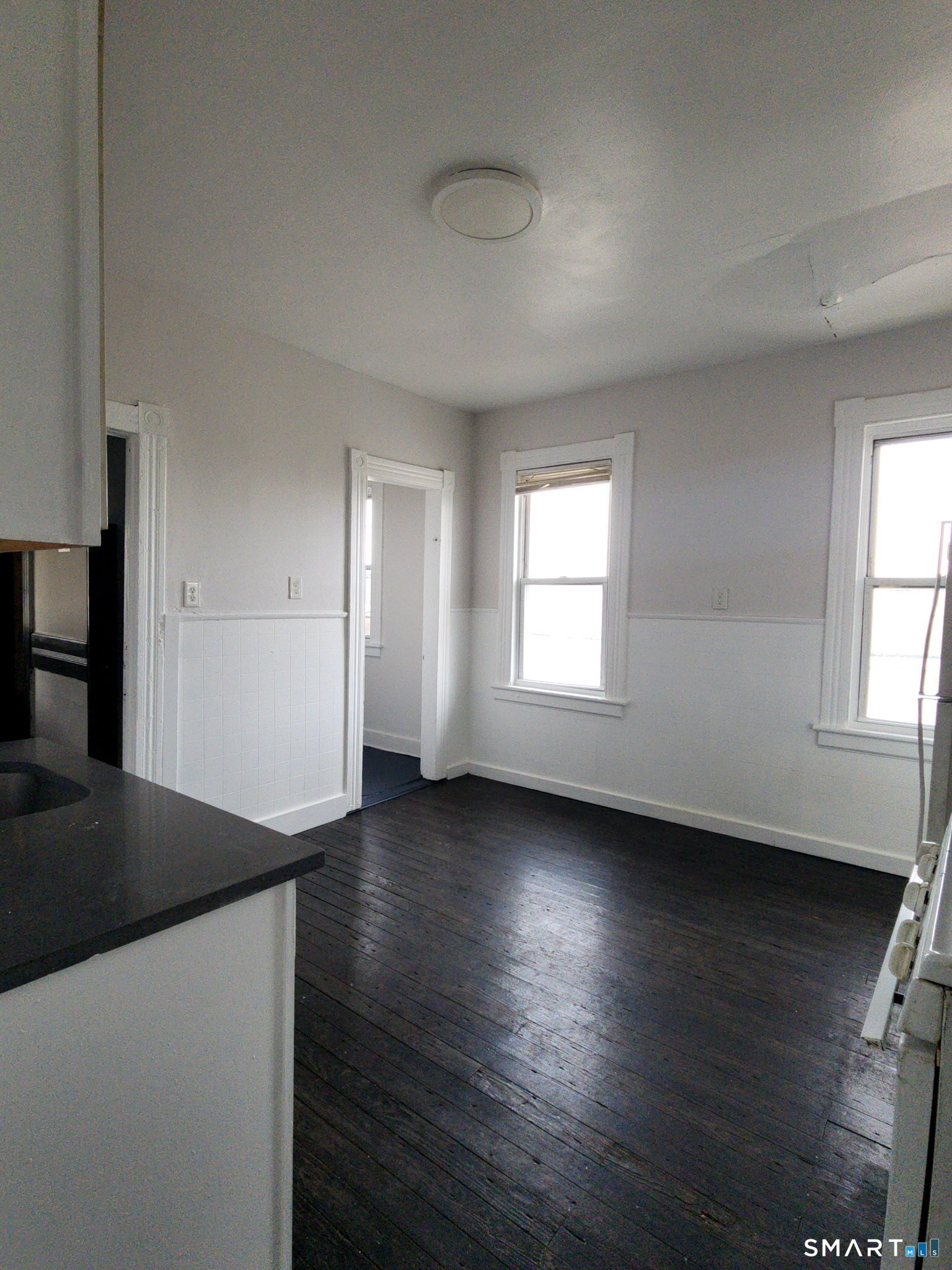 93-95 Baldwin Street, Unit 2 Bridgeport, CT 06607 - Photo 3 of 9 an empty room with wooden floor and windows