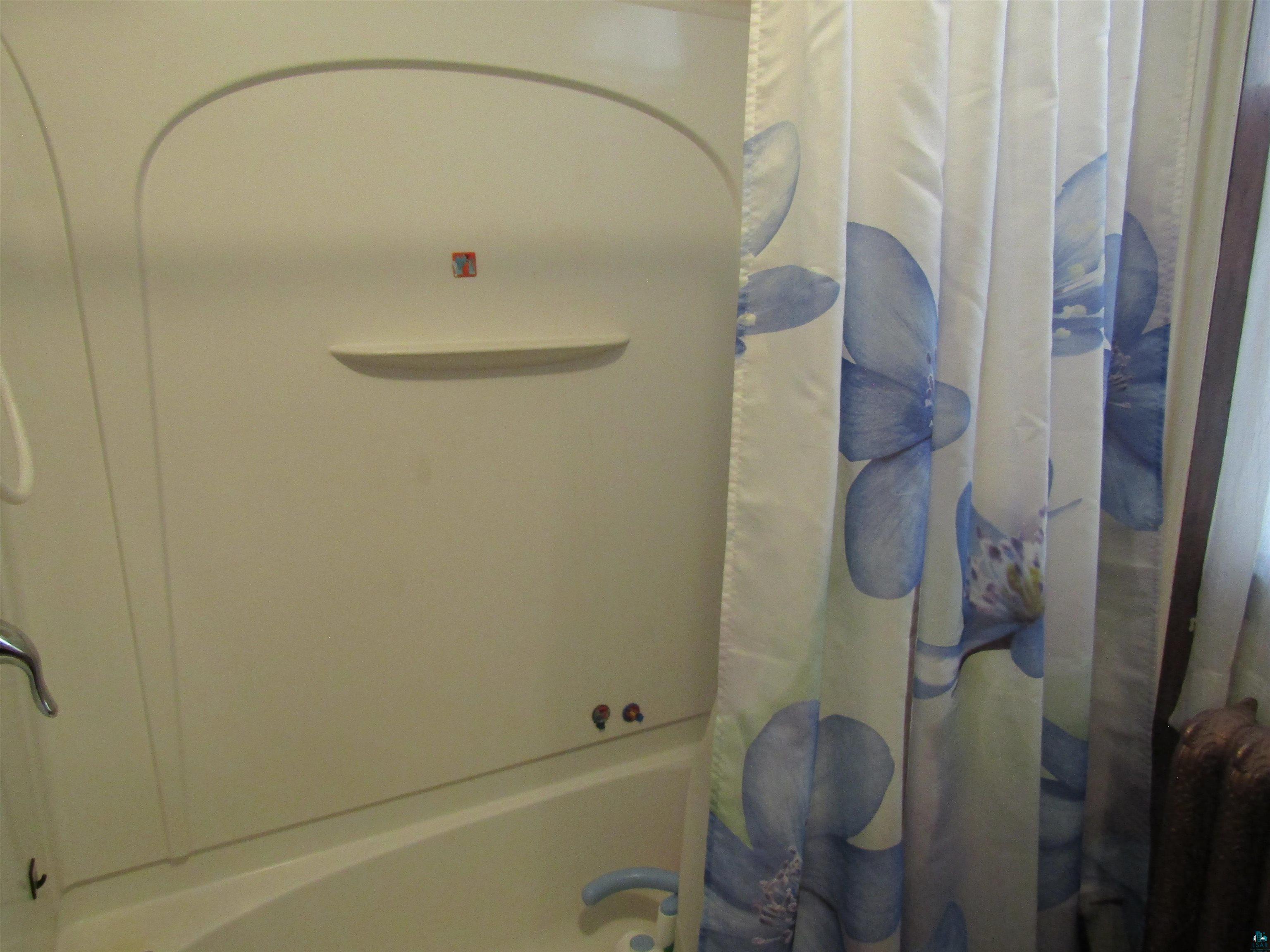 1115 Harrison Street Superior, WI 54880 - Photo 19 of 49 Enclosed shower and tub combination featuring a curved shower wall with an integrated shelf