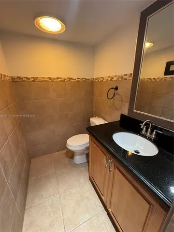 a bathroom with a granite countertop sink a toilet and a mirror
