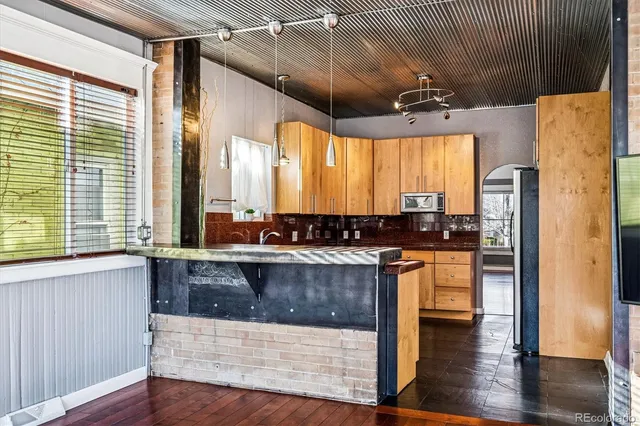 a kitchen with stainless steel appliances granite countertop a refrigerator a sink dishwasher a stove and white countertops with wooden floor