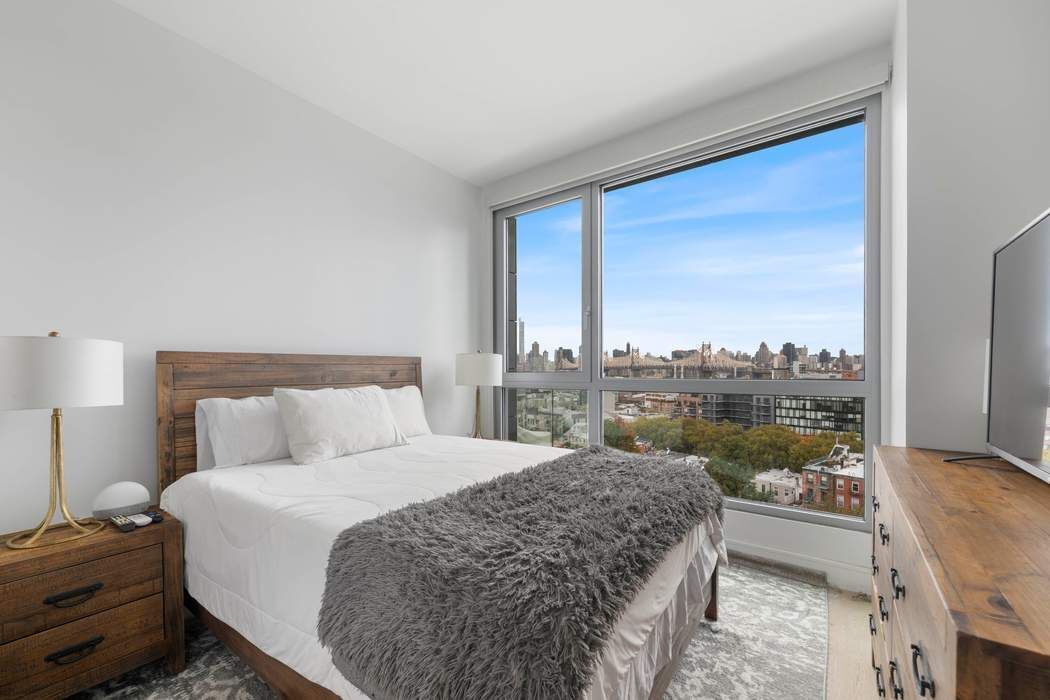 22-43 Jackson Avenue, Unit 11F Queens, NY 11101 - Photo 5 of 18 a bedroom with a bed and a large window