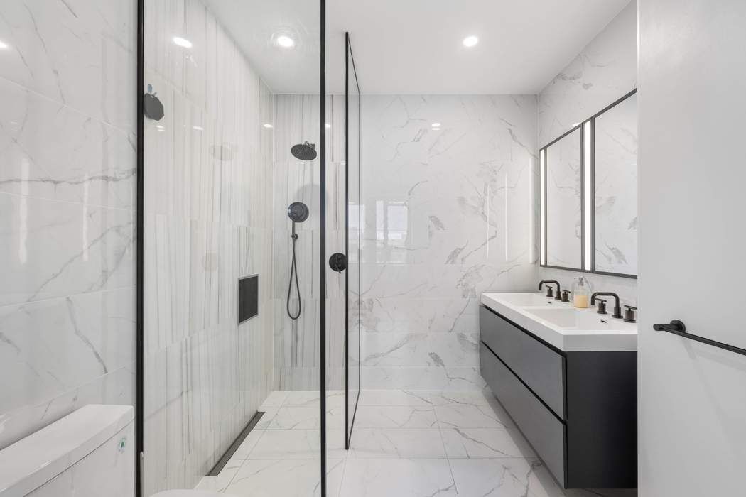 22-43 Jackson Avenue, Unit 11F Queens, NY 11101 - Photo 7 of 18 a bathroom with a bathtub sink mirror and shower