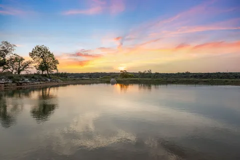 a view of a lake in between the field and covered with trees