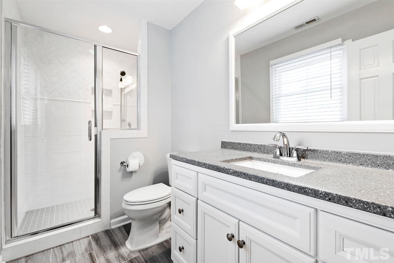 7605 Starling Court Raleigh, NC 27615 - Photo 20 of 30 a bathroom with a granite countertop sink toilet and shower