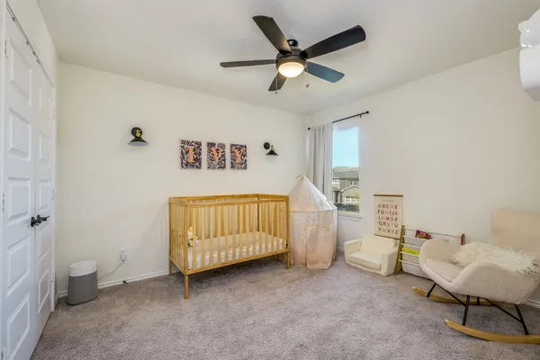 a bedroom with a baby bed a couch and a window