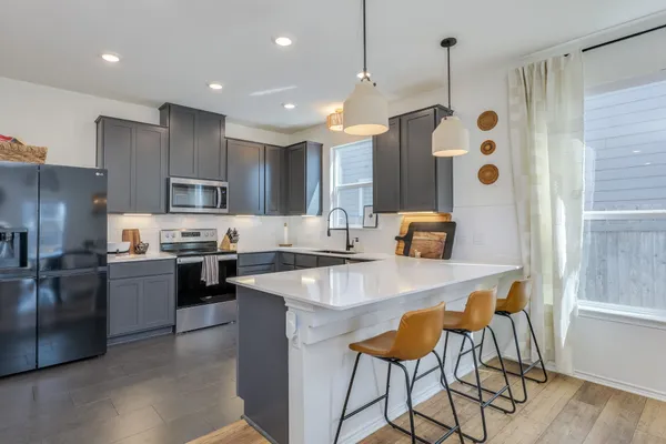 a kitchen with stainless steel appliances granite countertop a refrigerator a sink dishwasher a stove and a dining table with wooden floor