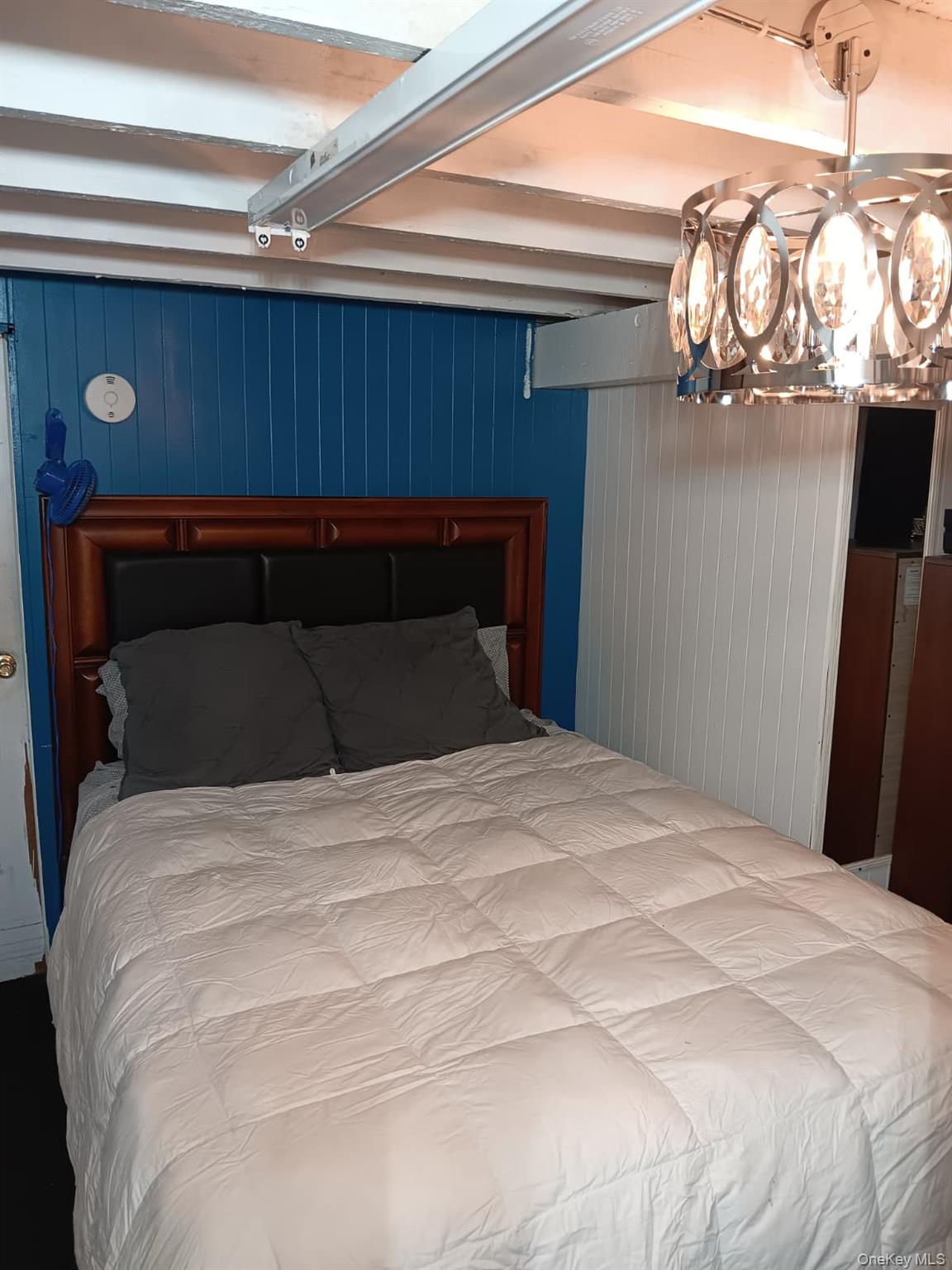 91-08 Sutter Avenue Queens, NY 11417 - Photo 19 of 32 Bedroom with beamed ceiling, a chandelier, and wood walls