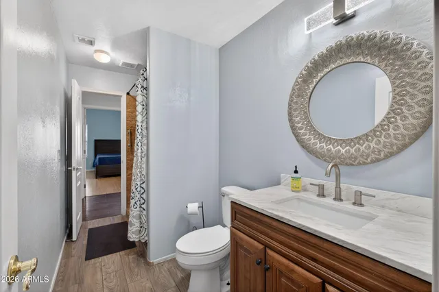 a bathroom with a granite countertop toilet a sink and a mirror