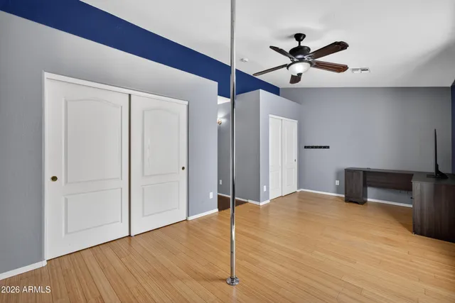 a view of empty room with wooden floor and ceiling fan