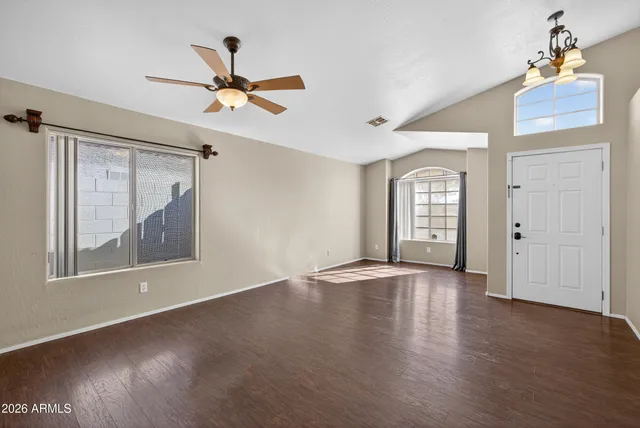 a view of empty room with wooden floor and fan