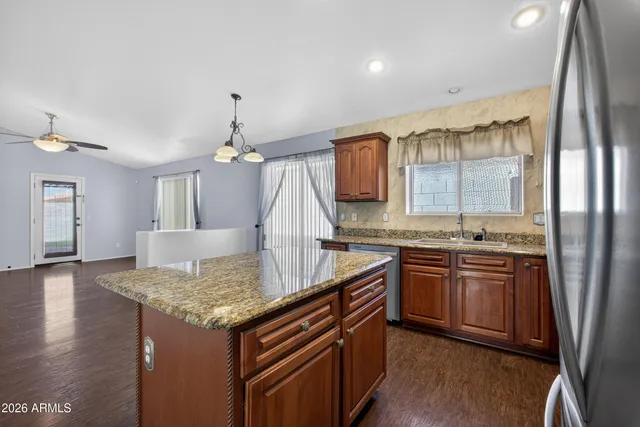 a kitchen with granite countertop kitchen island stainless steel appliances a sink stove and wooden floor