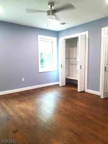 an empty room with chandelier fan and windows