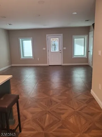 a view of an empty room with window and wooden floor
