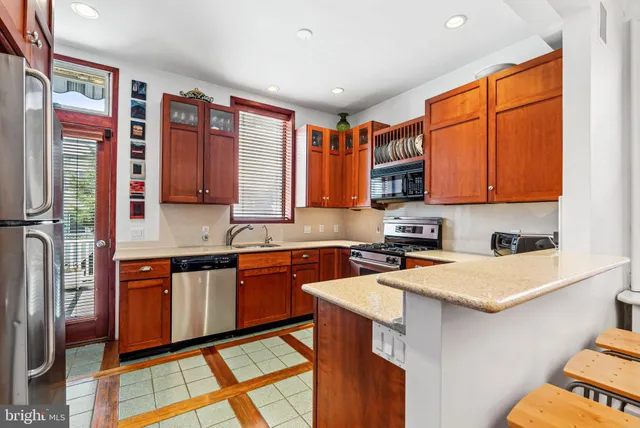 a kitchen with stainless steel appliances granite countertop a stove a sink dishwasher and a refrigerator with wooden cabinets
