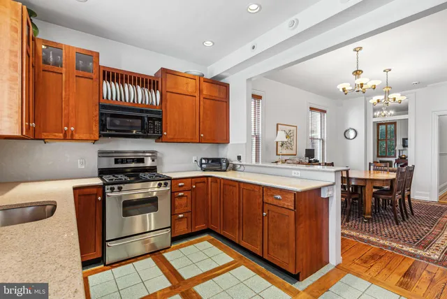 a kitchen with stainless steel appliances granite countertop a stove top oven a sink dishwasher and white cabinets with wooden floor