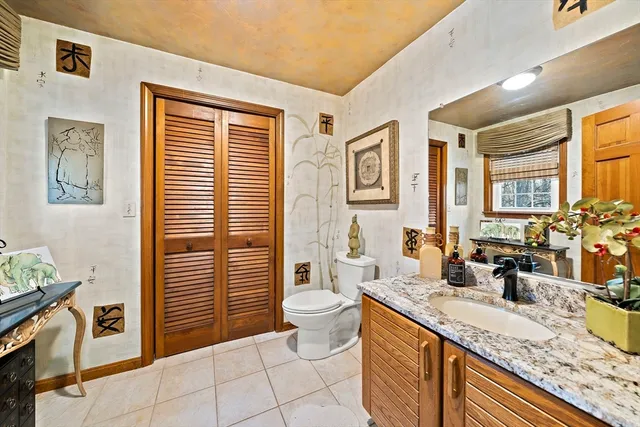 a spacious bathroom with a granite countertop sink a toilet a mirror and shower