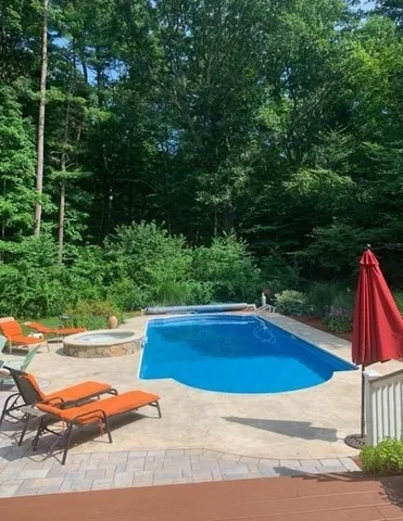 a view of swimming pool with lawn chairs under an umbrella