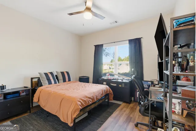 a large bedroom with wooden floor and bed