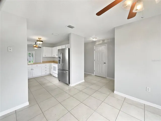 an empty room with a chandelier fan and windows