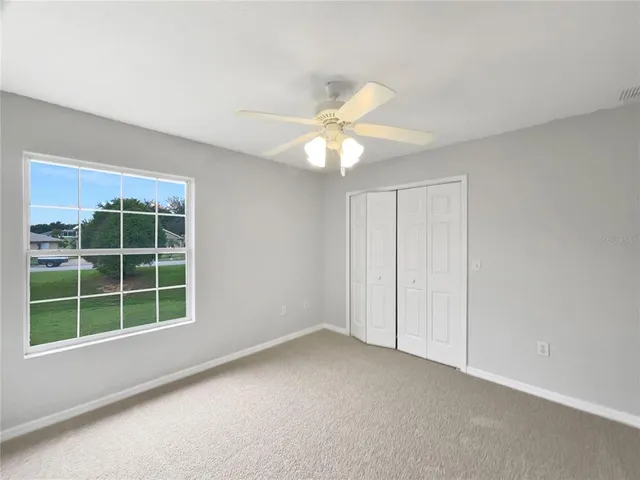 an empty room with a chandelier fan and windows
