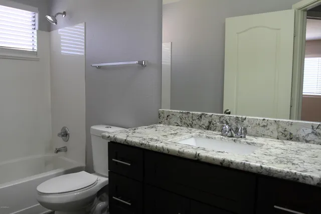 a bathroom with a granite countertop sink toilet and shower