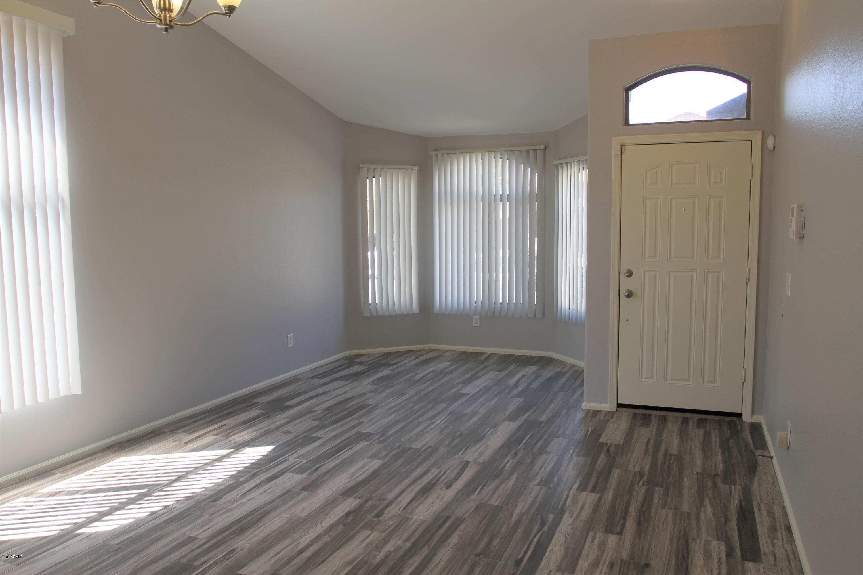 12409 West San Juan Avenue Litchfield Park, AZ 85340 - Photo 3 of 12 an empty room with wooden floor and windows