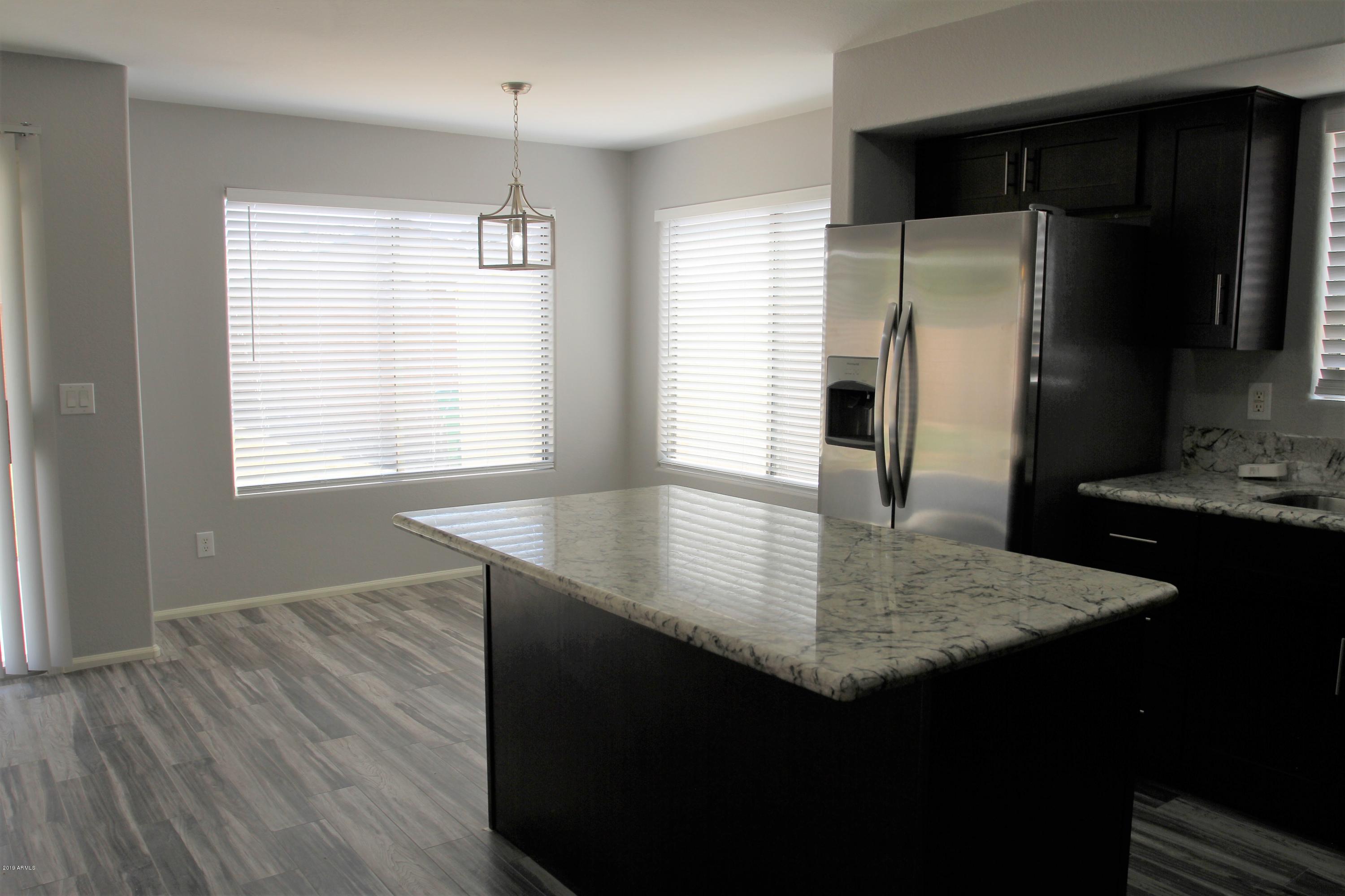 12409 West San Juan Avenue Litchfield Park, AZ 85340 - Photo 5 of 12 a kitchen with kitchen island a counter top space appliances and a window