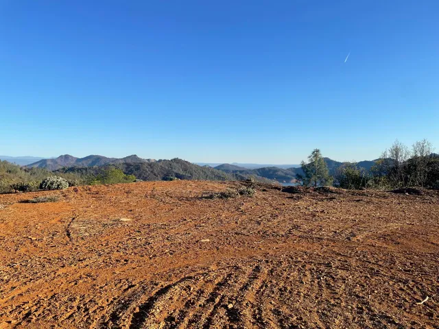 a view of a lush green field with mountains in the background