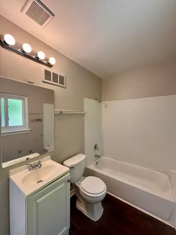 a bathroom with a toilet sink vanity tub and shower