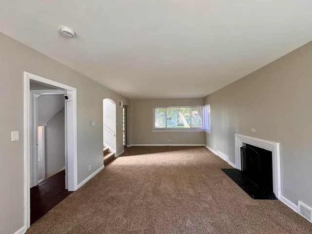 an empty room with windows and fireplace