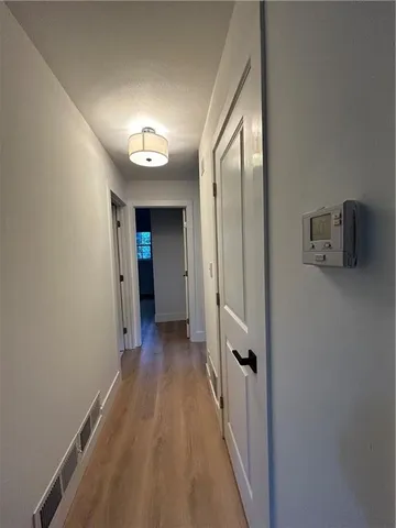 a view of a hallway with wooden floor and a bathroom
