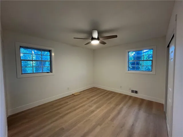 a view of an empty room with window and chandelier fan