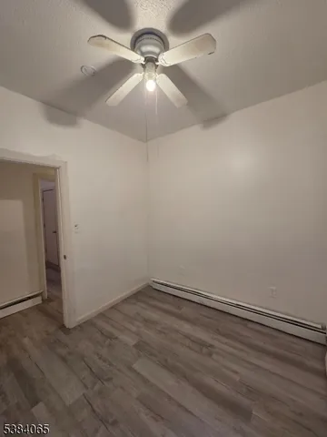 an empty room with wooden floor and fan