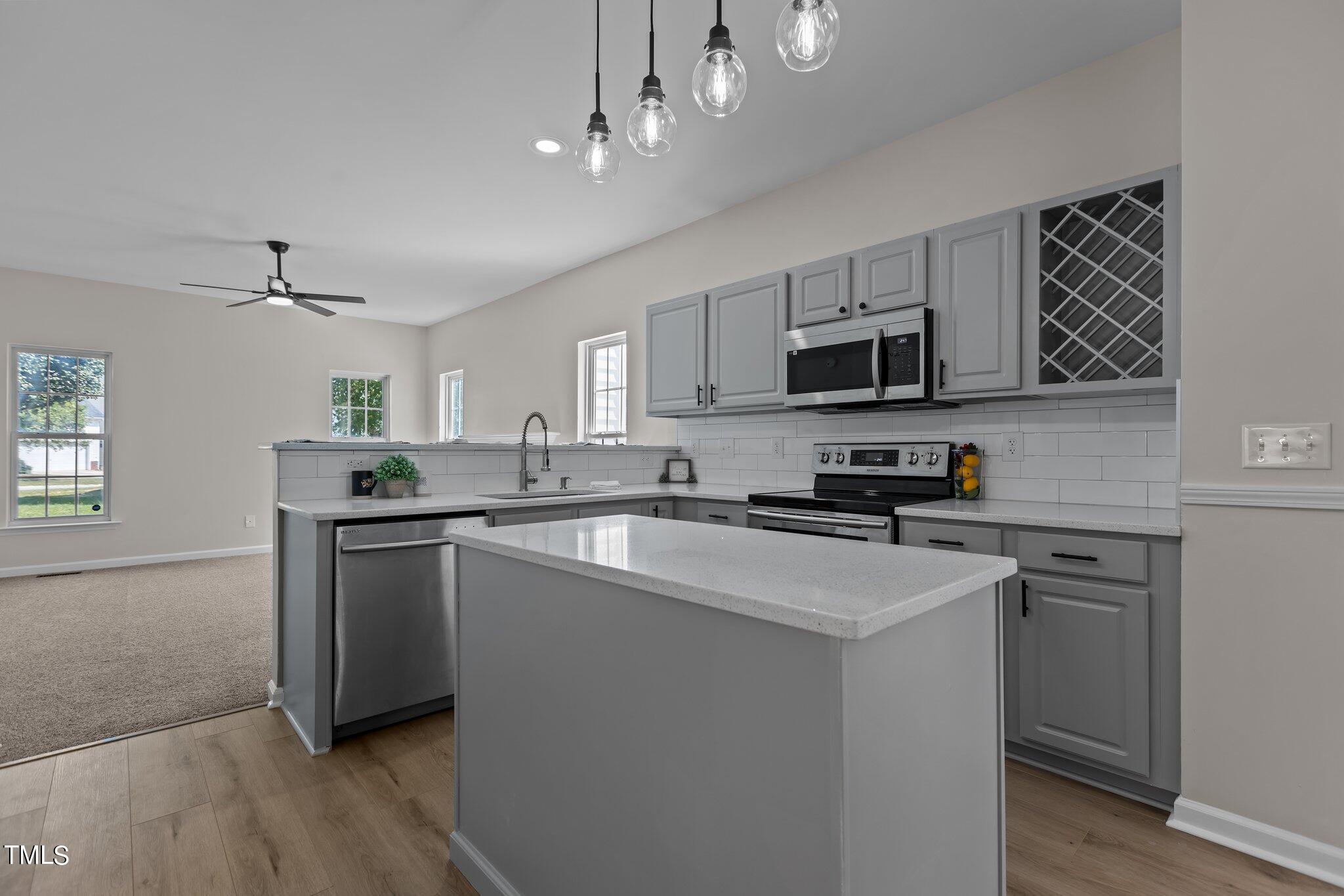 3225 Forest Mill Circle Raleigh, NC 27616 - Photo 9 of 36 a kitchen with stainless steel appliances granite countertop a sink a stove a microwave a refrigerator a center island and cabinets