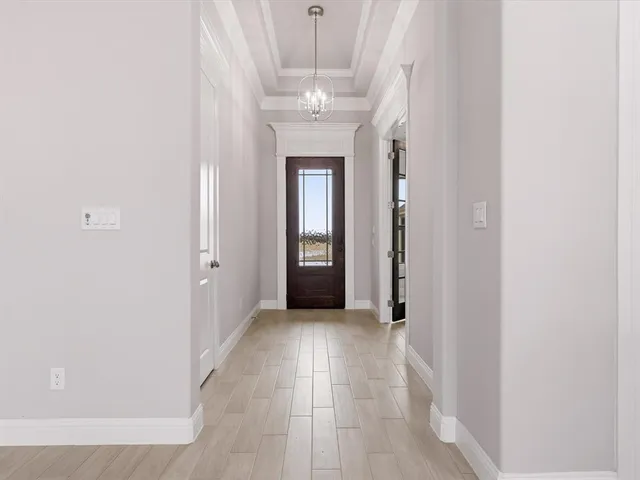 a view of a hallway with wooden floor and chandelier