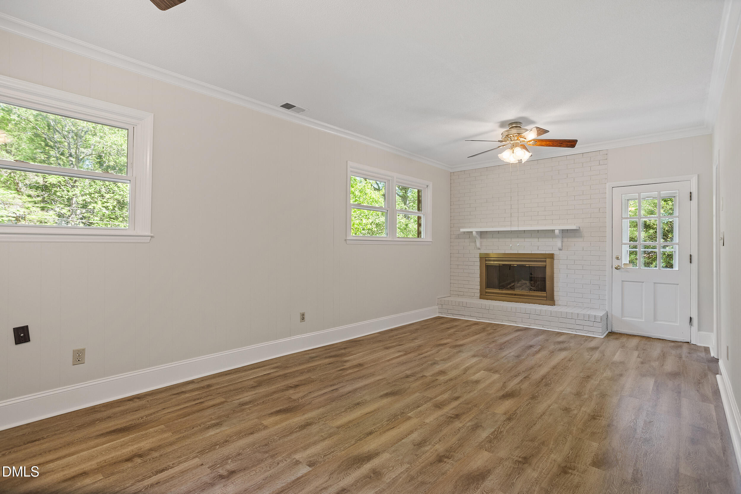 4711 Tanglewood Drive Raleigh, NC 27612 - Photo 16 of 39 an empty room with windows fireplace and wooden floor