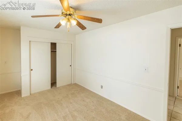 an empty room with a window and a fan