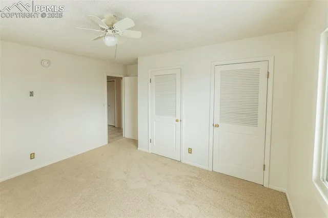 an empty room with a window and a ceiling fan