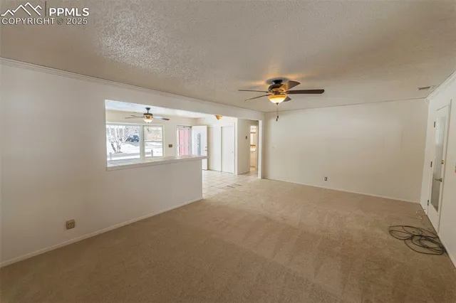 an empty room with chandelier fan and windows