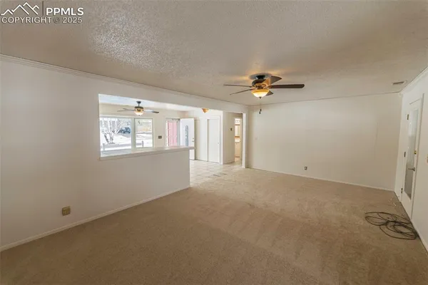 an empty room with chandelier fan and windows