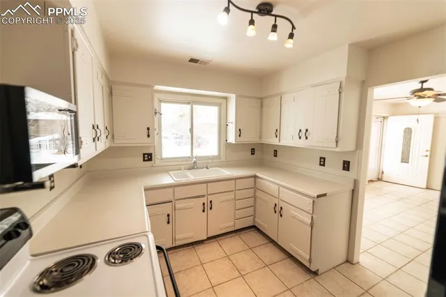 a view of an empty room with window and chandelier fan