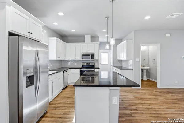 a kitchen with stainless steel appliances granite countertop a refrigerator a oven and a sink