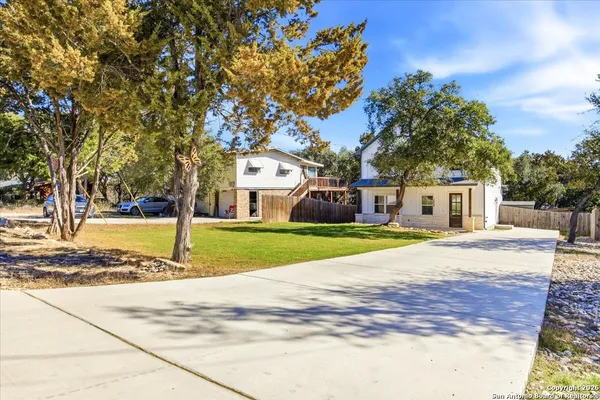 a view of a house with a big yard and large trees