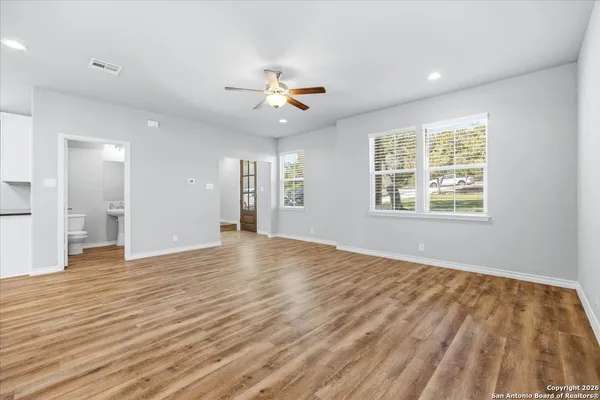 a view of an empty room with window and wooden floor