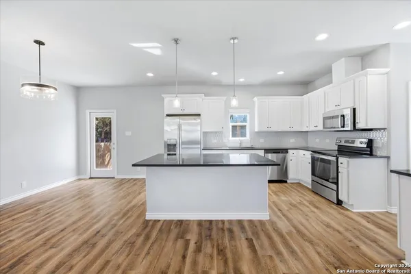 a large kitchen with granite countertop a large counter top a sink stainless steel appliances and cabinets