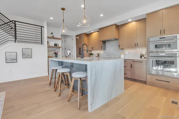 a large kitchen with stainless steel appliances kitchen island granite countertop a refrigerator a sink and white cabinets