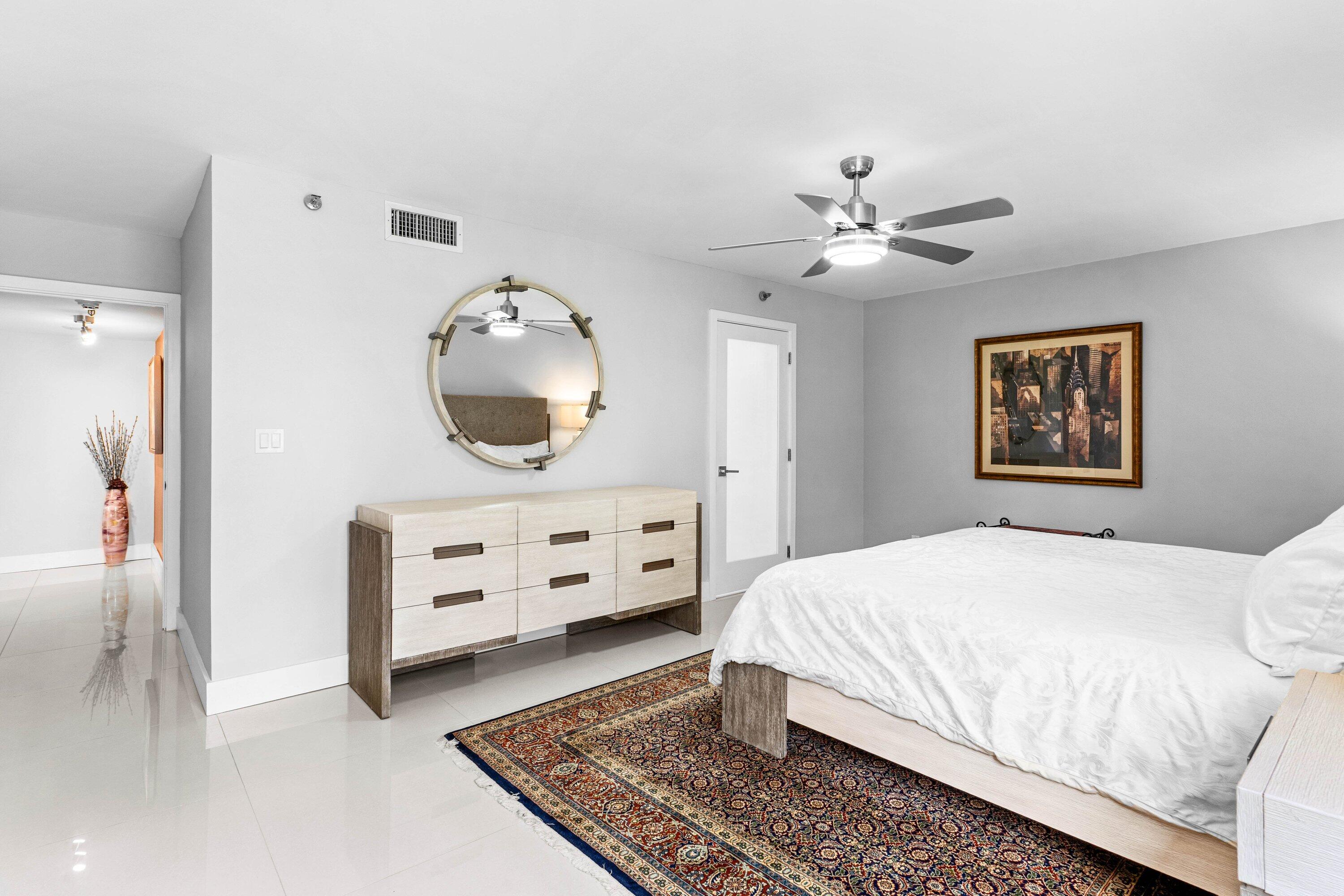 7572 Regency Lake Drive, Unit 301 Boca Raton, FL 33433 - Photo 20 of 38 a bedroom with a bed and a chandelier